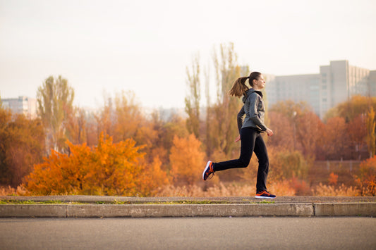 Runner in motion on a paved path in front of brilliant orange autumn foliage